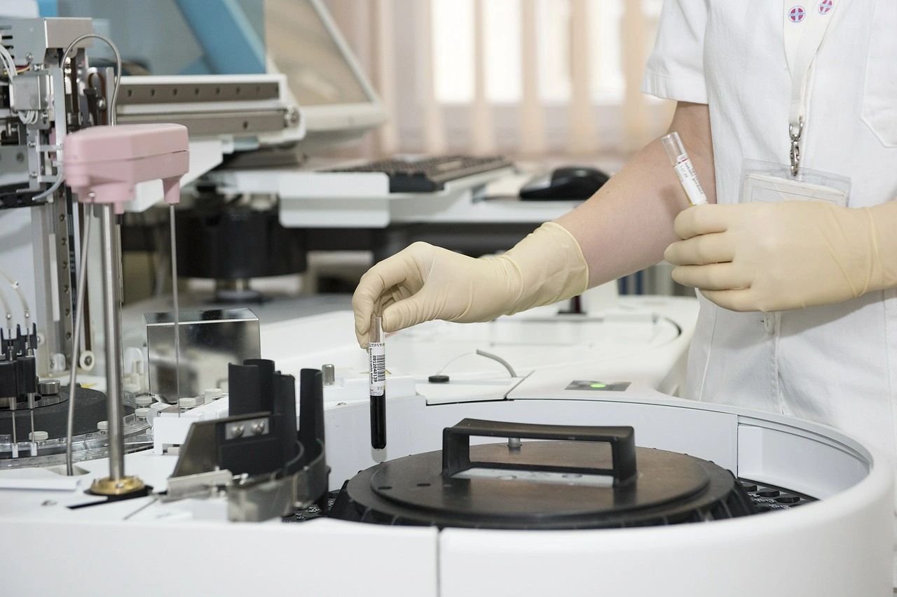 a clinical laboratory worker inserting specimen tubes into a centrifuge for a diagnostic test
