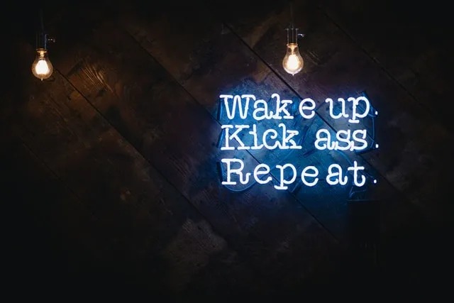 Neon sign saying Wake up. Kick ass. Repeat.